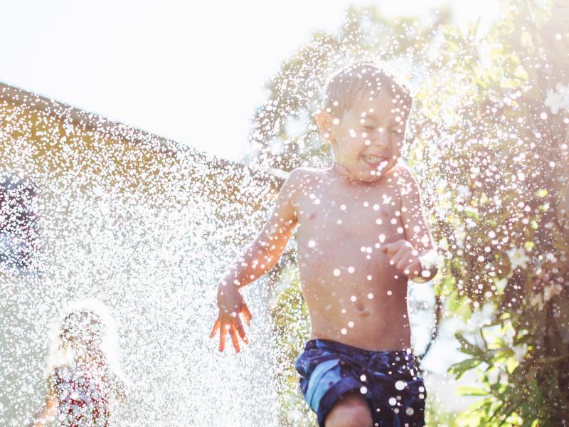 Children running through sprinkler